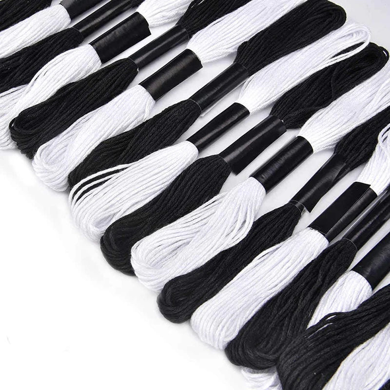 A collection of 24 embroidery floss spools in alternating white and black colors.