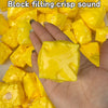 A hand is holding and squeezing bright yellow, squishy, cube-shaped fidget toys.