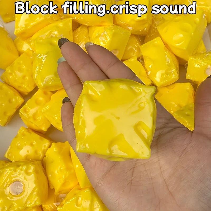 A hand is holding and squeezing bright yellow, squishy, cube-shaped fidget toys.