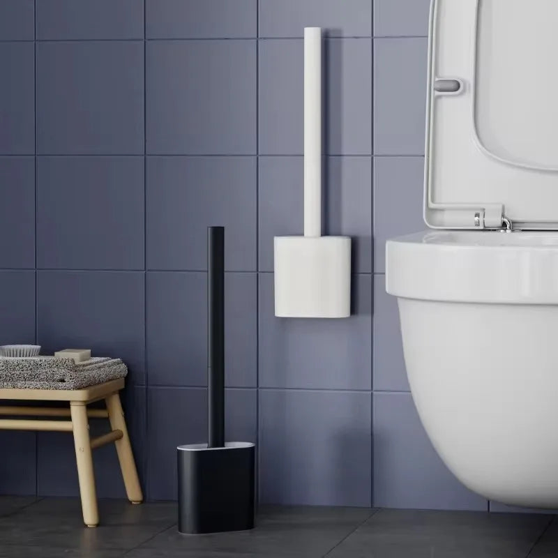 A wall-mounted toilet brush set with a black handle and white silicone head is mounted on a gray tiled wall.