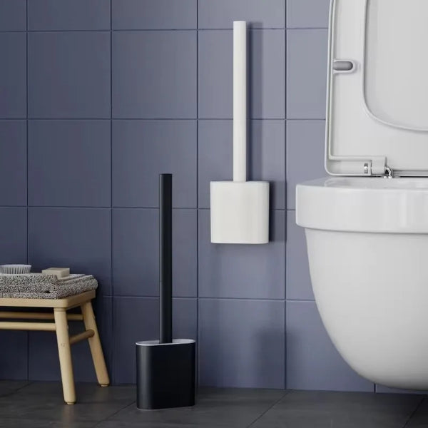 A wall-mounted toilet brush set with a black handle and white silicone head is mounted on a gray tiled wall.