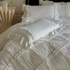 White ruffled duvet cover set with matching pillowcases and a decorative bed display.