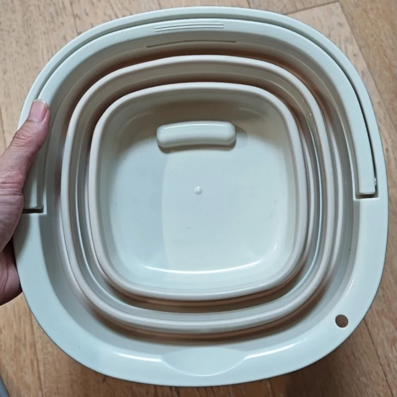 A white collapsible outdoor bucket with a carry handle is shown from above.