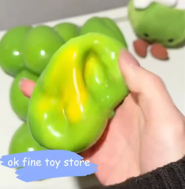 Eine Hand hält einen leuchtend grünen, quetschbaren Stressball in Form einer Mango.