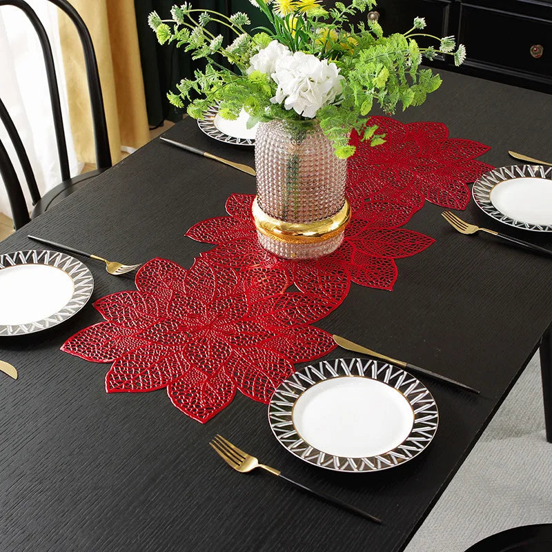A set of ornate red floral PVC table runners and placemats with gold accents displayed on a black table.