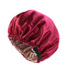 A deep magenta satin sleep bonnet with a gathered edge and adjustable strap.