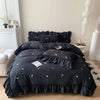 A black duvet cover set with rose embroidery and lace details displayed on a bed.