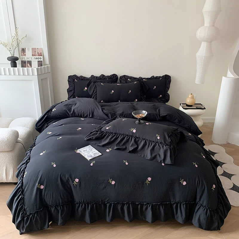 A black duvet cover set with rose embroidery and lace details displayed on a bed.