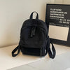 A black Japanese corduroy casual backpack resting on a white surface next to a framed sign.