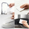 Hands are using white magic eraser sponges to clean a kitchen faucet and a white leather shoe.