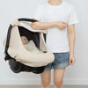 A person holds a beige breathable 2-in-1 car seat cover and mosquito net for babies.