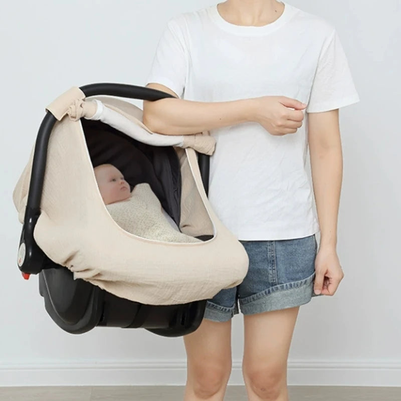 A person holds a beige breathable 2-in-1 car seat cover and mosquito net for babies.