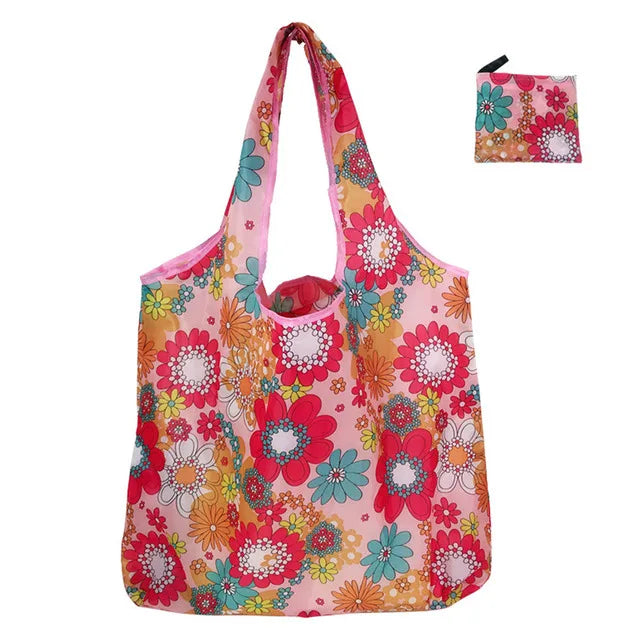 A pink and floral patterned reusable nylon shopping tote bag with a small matching pouch.