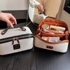 Elegante Reise-Make-up-Organizer-Tasche aus beige und kupferfarbener Leder auf dunklem Holz
