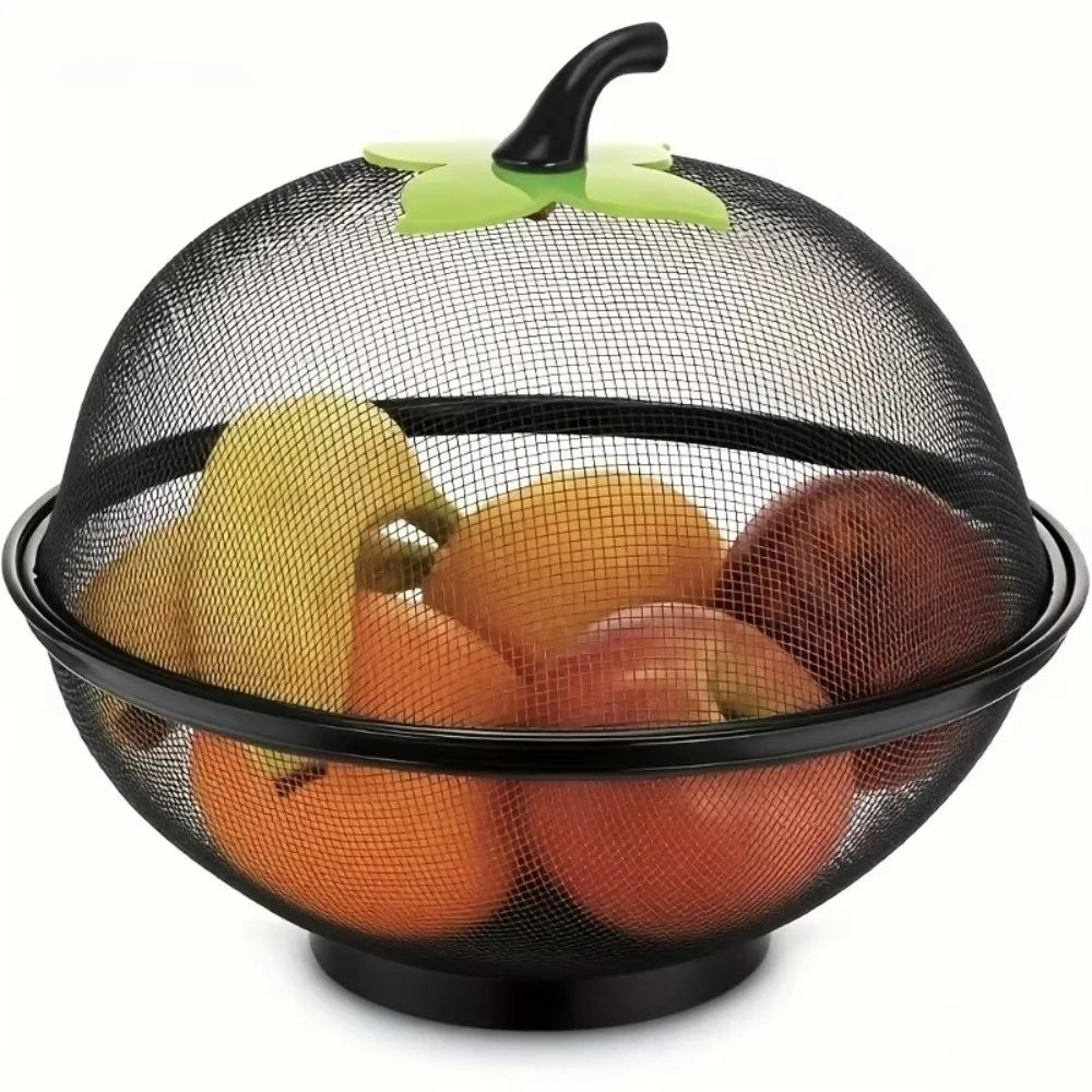 Black metal fruit basket with a mesh cover and a green handle, holding various fruits.