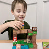 A young boy is building a wooden magnetic block house structure with other blocks on a white table.
