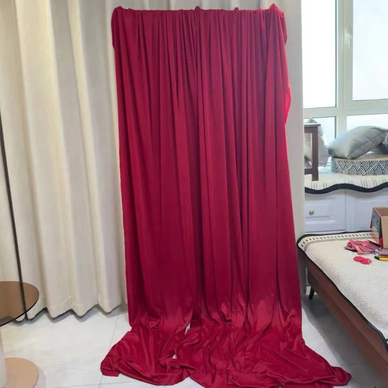 A floor-length drape of elegant burgundy stretch jersey fabric hanging in a vertical fold.