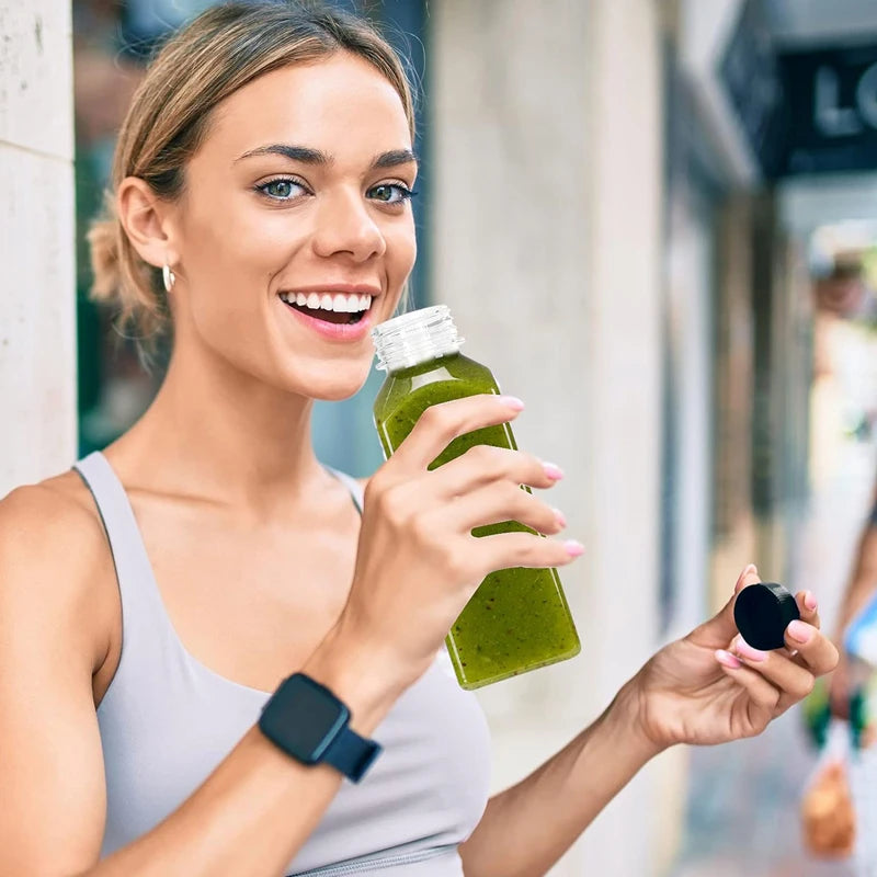 A woman holds a green juice bottle with a tamper-evident cap, smiling while looking at the camera.