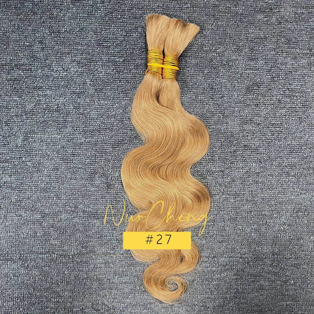 Un paquet de cheveux blonds ondulés tressés humains attachés par un fil d'or sur un fond de tissu gris.