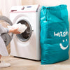 A large teal drawstring laundry bag is shown next to a white washing machine.