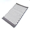 Gray acupressure mat with numerous white suction cup dots for pain relief and relaxation