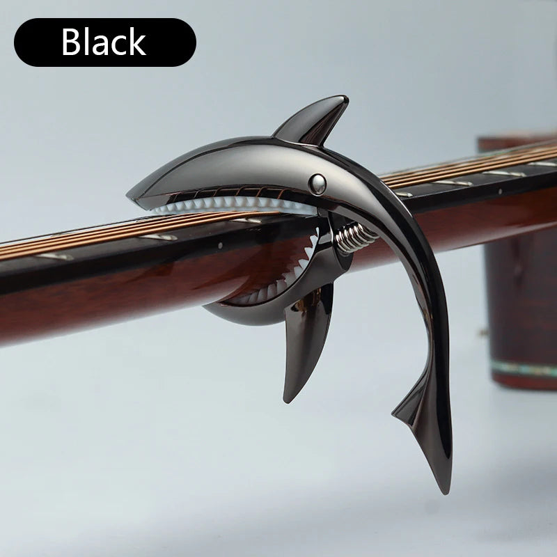 Black shark-design guitar capo with zinc alloy build shown on a wooden neck.