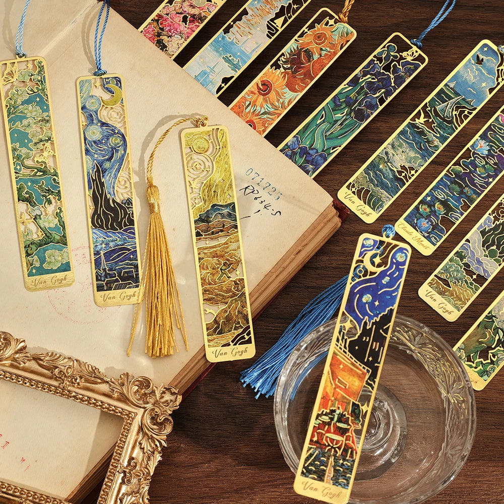 A collection of twelve vintage metal bookmarks with colorful designs and long tassels displayed on a wooden surface.
