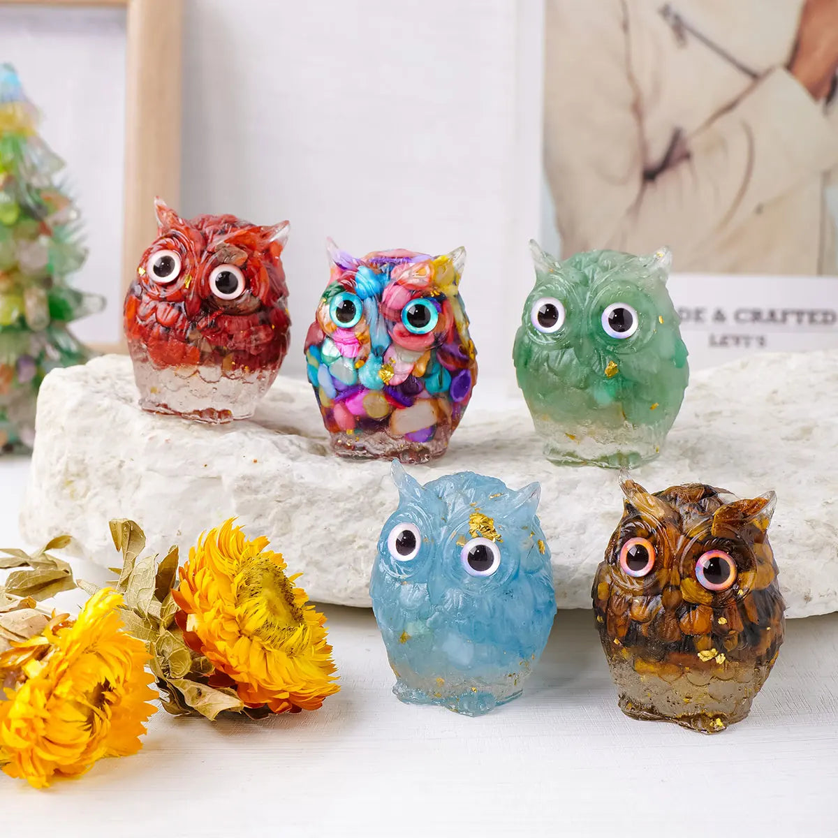 A collection of handcrafted crystal owl figurines in various colors and finishes displayed on a white surface.