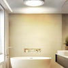 Modern white oval bathtub in a bright bathroom with recessed lighting and a window.