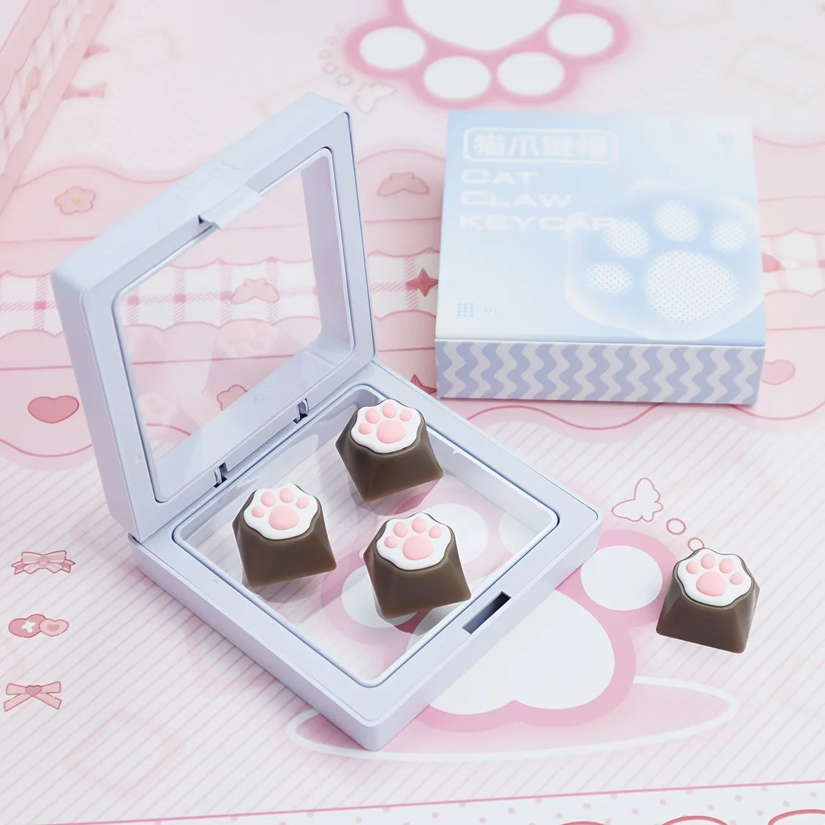 A clear plastic case holds silicone cat paw keycaps and a box for MX switches.
