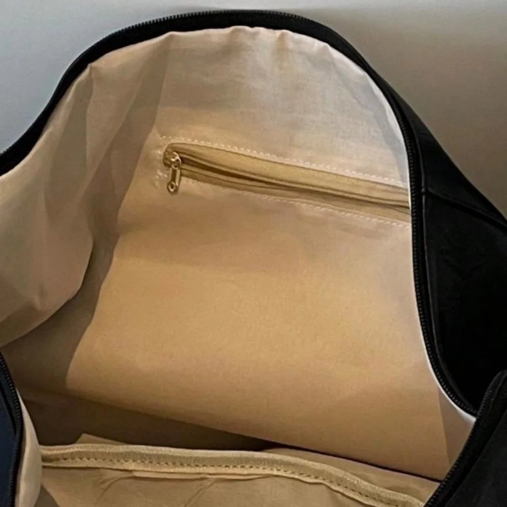 Interior view of a black dumpling-style PU crossbody bag with a light beige lining and zipper.
