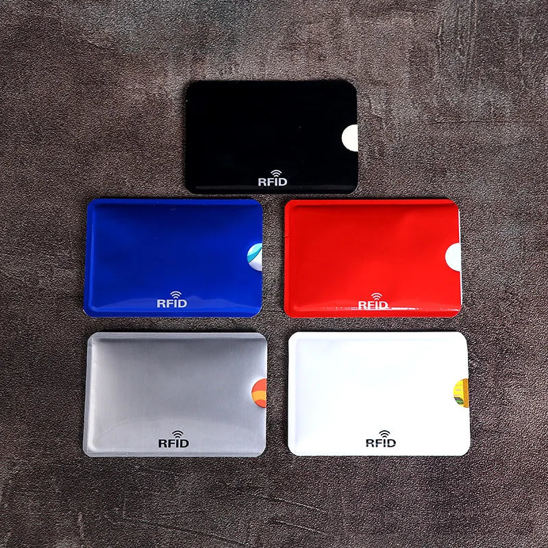 A set of four RFID blocking card sleeves in black, blue, red, and white are displayed on a dark surface.