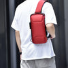 Un hombre con una camiseta blanca sostiene una bolsa cruz multifuncional roja antirrobo.