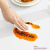 A hand wipes orange food from a yellow bread slice using a white cloth, demonstrating easy decontamination.
