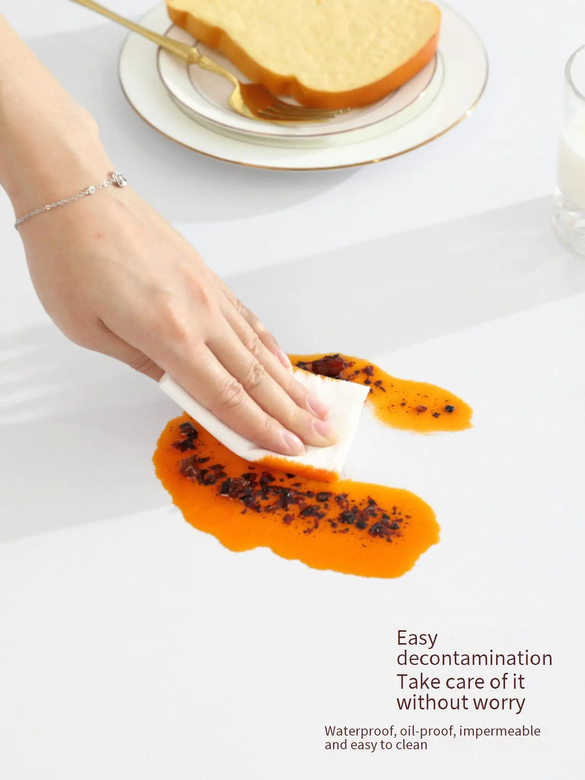 A hand wipes orange food from a yellow bread slice using a white cloth, demonstrating easy decontamination.