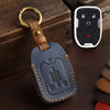 A dark blue leather key fob case with a brass ring attached, resting on a dark surface.