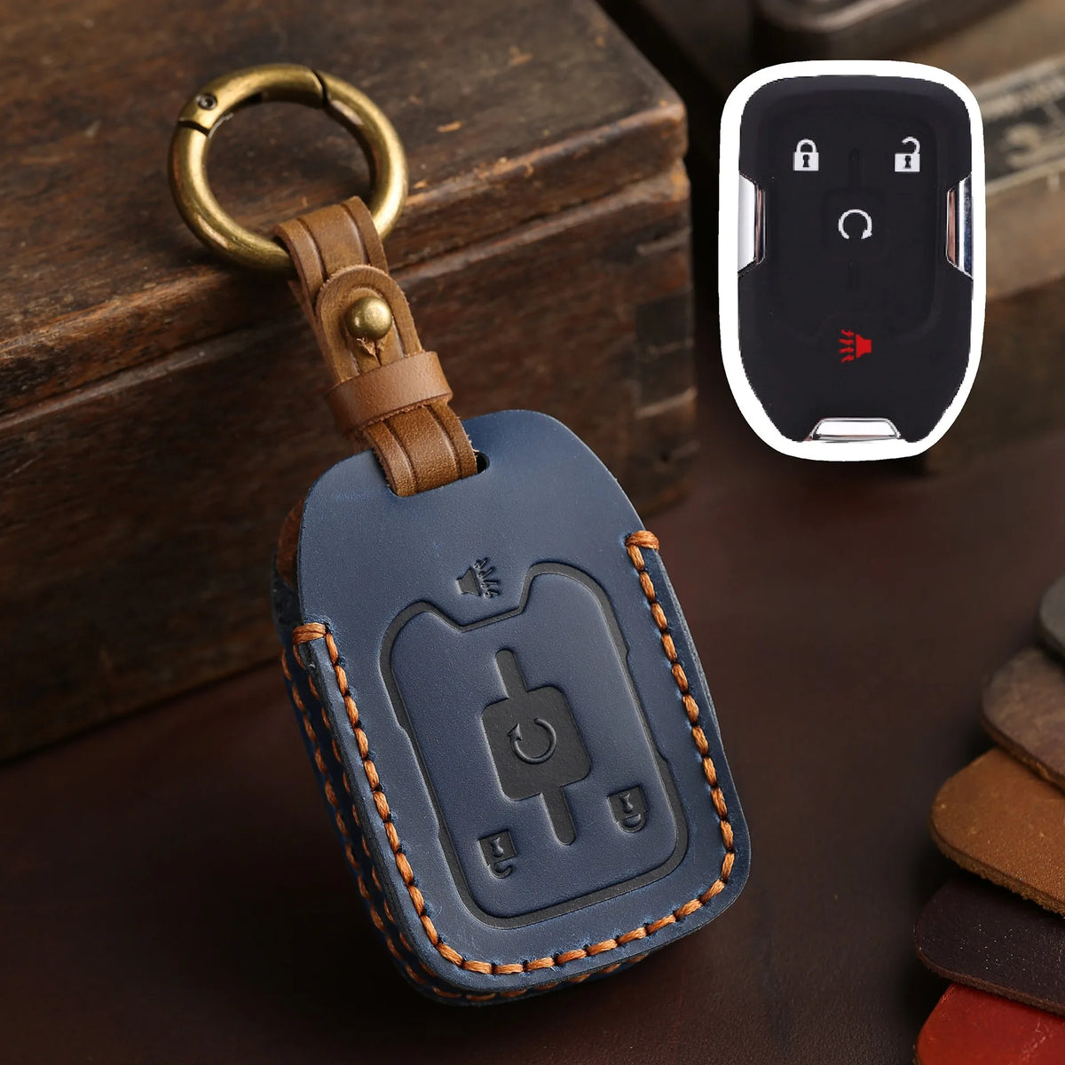 A dark blue leather key fob case with a brass ring attached, resting on a dark surface.