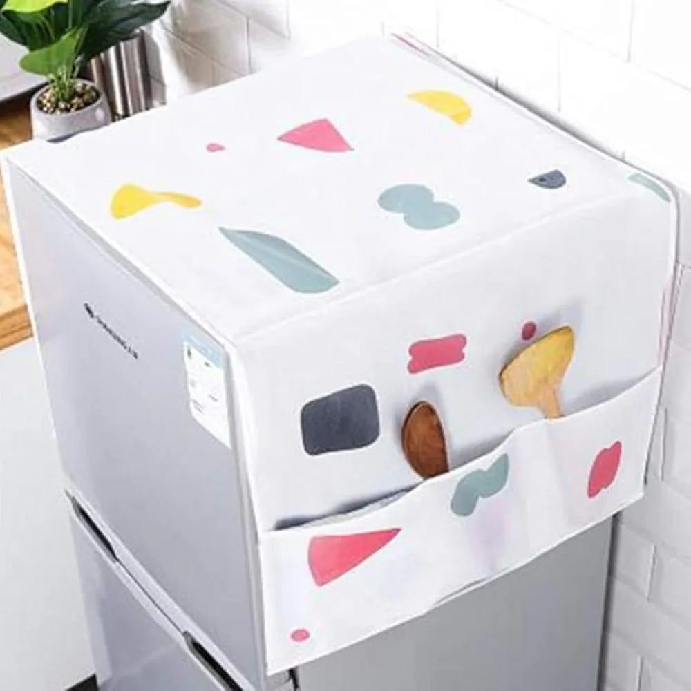 A white refrigerator dust cover with colorful fabric accents and storage pockets is shown on a kitchen counter.