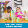 A child is using a telescoping fishing toy to play a surprise gameplay game with other toys on a wooden table.
