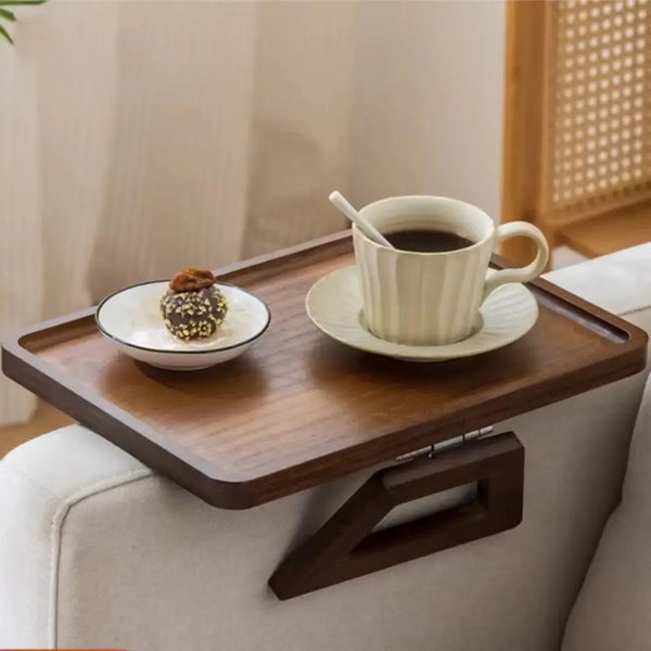 Raccourci de dossier de canapé en bois pliante contenant une tasse et une petite pâtisserie sur une surface claire.