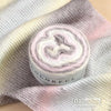 Roll of colorful gradient cake yarn on a purple fabric background