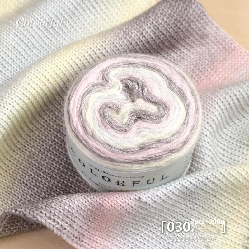 Roll of colorful gradient cake yarn on a purple fabric background