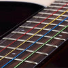 Close-up view of six color-coded acoustic guitar strings laid out on the fretboard.