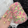 A hand holds a ball of pink and yellow variegated yarn for knitting or crochet