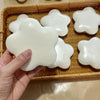A hand holds a white, soft squeeze star-shaped stress relief toy resting in a woven basket.