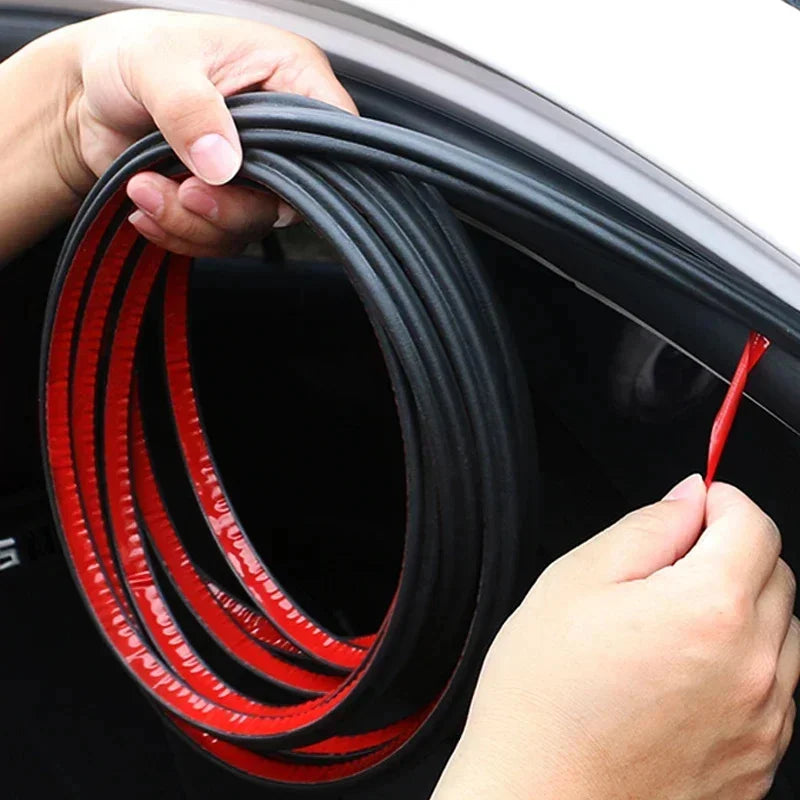 A hand is holding a coiled red and black flexible rubber seal strip used for car door weatherproofing.