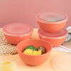 A set of orange airtight storage bowls and lids with some yellow corn and a piece of broccoli inside.