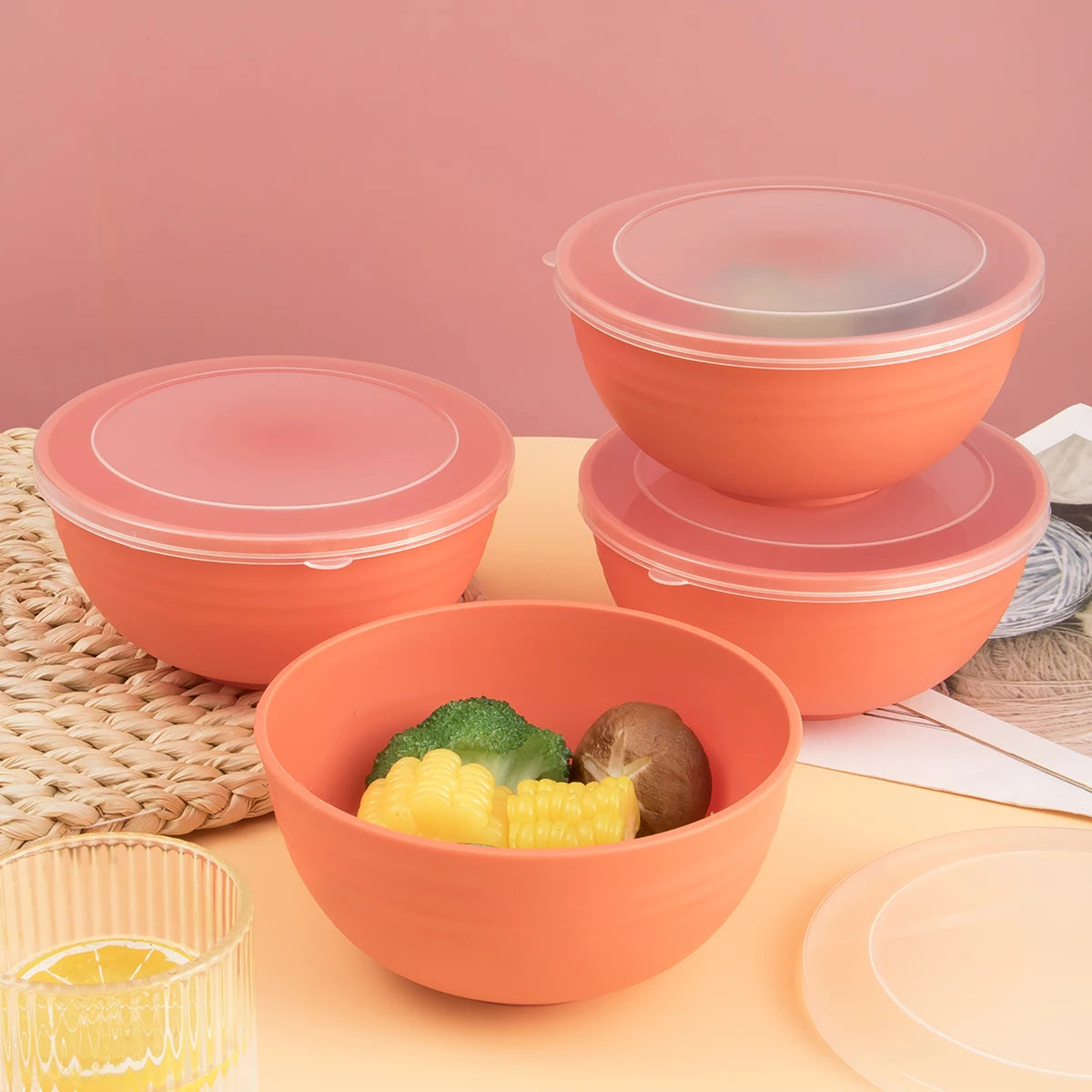 A set of orange airtight storage bowls and lids with some yellow corn and a piece of broccoli inside.