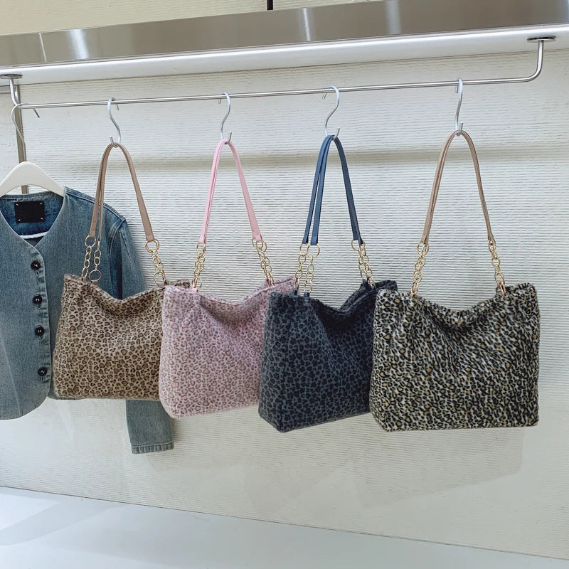 Cinq sacs en toile à imprimé léopard accrochés sur un support métallique avec des sangles en cuir