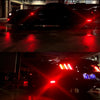 Close-up of red LED rear side marker lights on a black Ford Mustang in a dark environment.